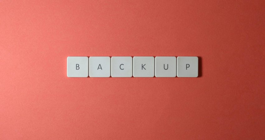 Free Close-up of keyboard keys spelling 'BACKUP' placed on a coral-colored surface. Stock Photo